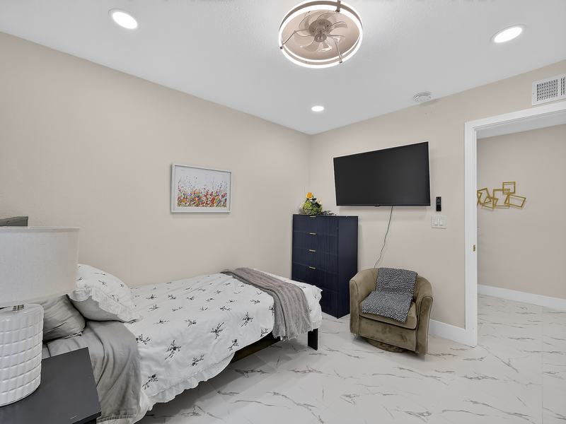A resident bedroom with a twin bed, navy dresser, and wall-mounted TV