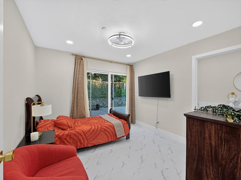 A resident bedroom with a wood sleigh headboard, orange bedspread, and reading chair