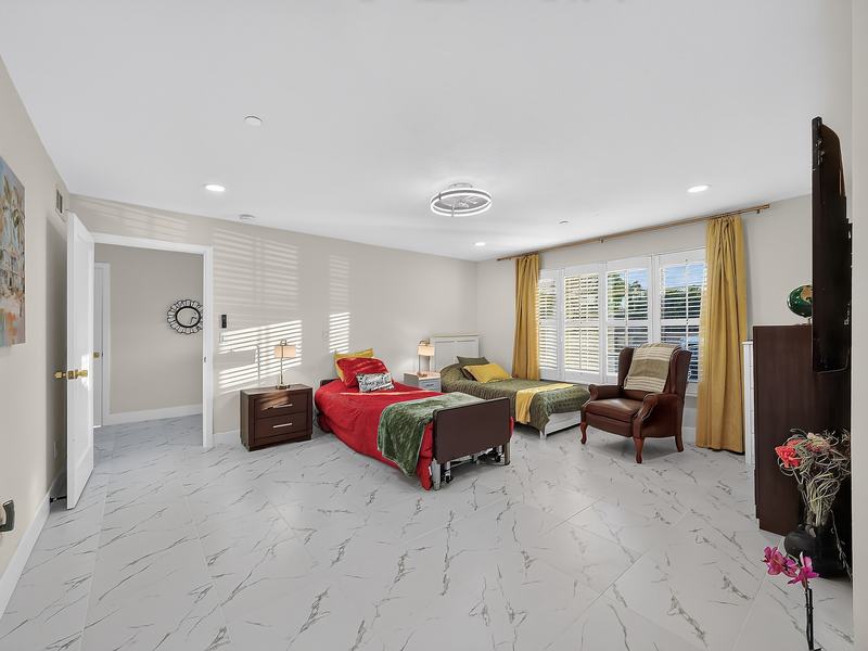 A shared bedroom with two beds, an armchair, and shuttered windows onto the garden