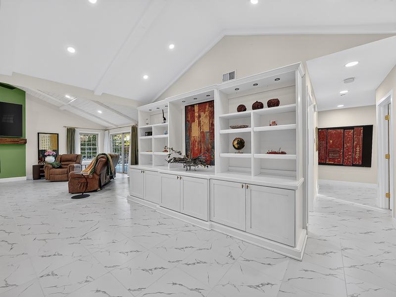 White built-in shelves and cabinets dividing the great room from the hallway