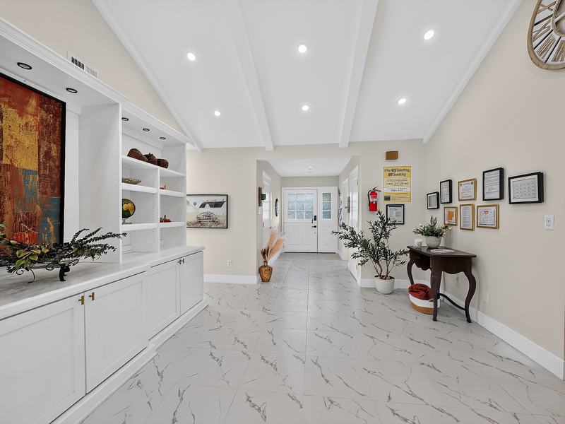 The main entry hall leading to the front door, with a console table and plants