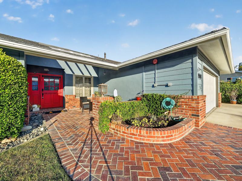 The front courtyard: a red double door, brick paving, and a raised brick planter