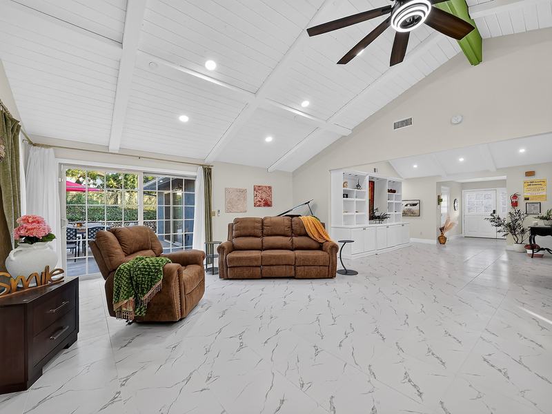 The living room with sliding doors open onto the back patio, a green throw over the recliner